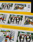 Three souvenir stamp booklets lay, overlapping, on a black surface.